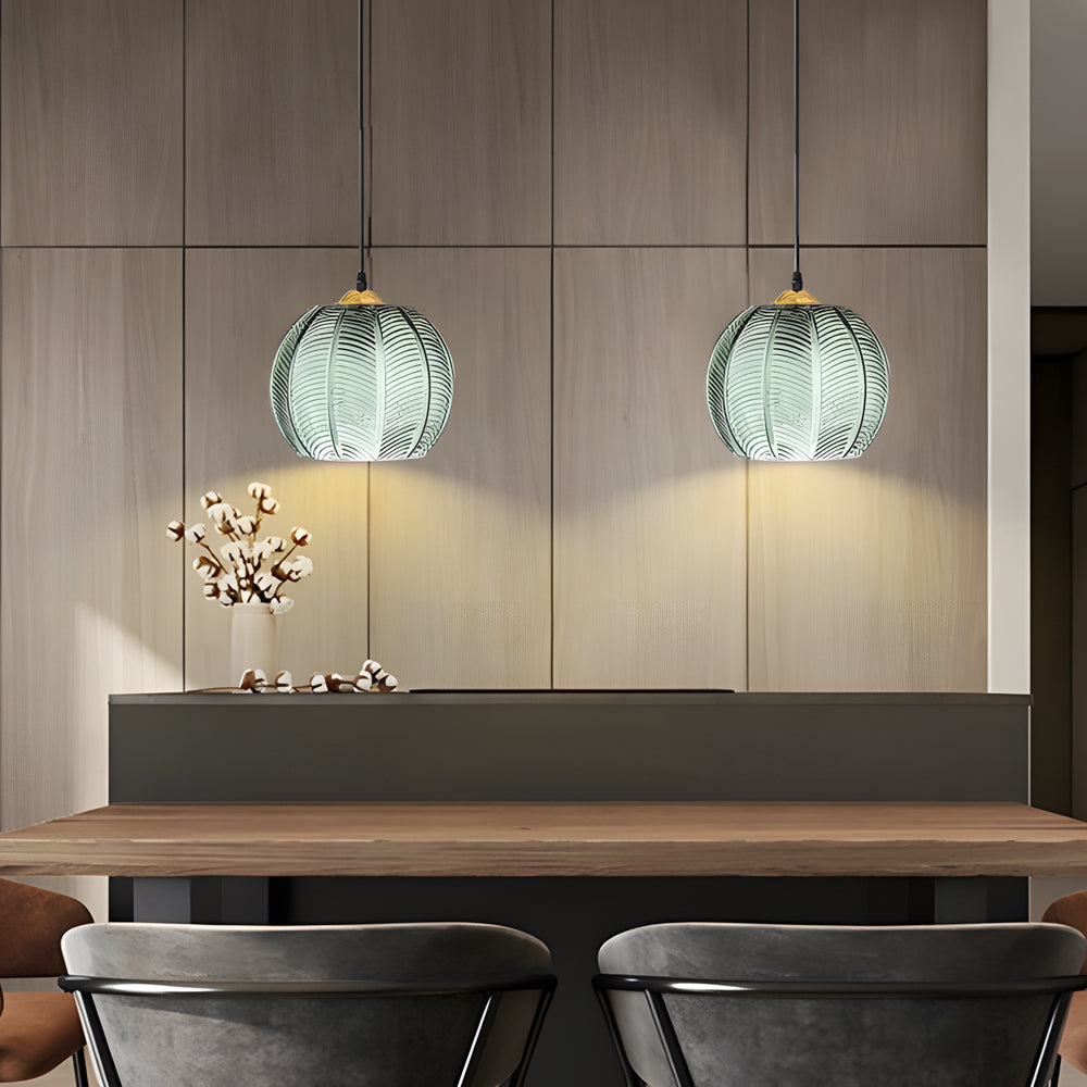 Pair of green glass pendant lights mounted above a modern dining booth seating area.