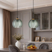 Green glass pendant lights hanging above a classic dining table in an elegant interior.