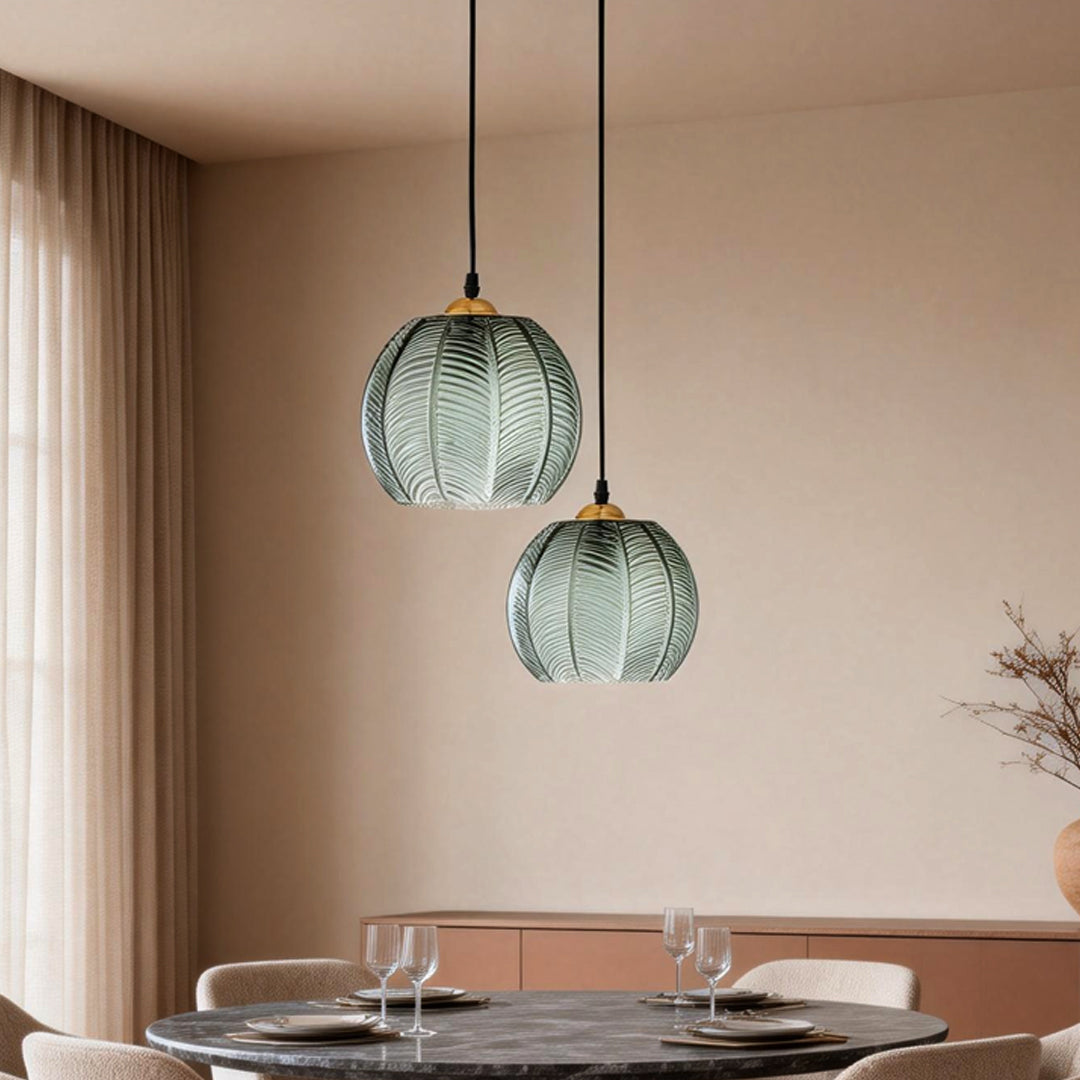 Single green glass pendant light suspended over a round dining table with warm lighting.