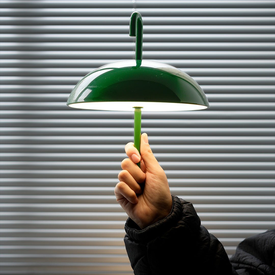 Green dome USB rechargeable table lamp held by hand demonstrating portable functionality
