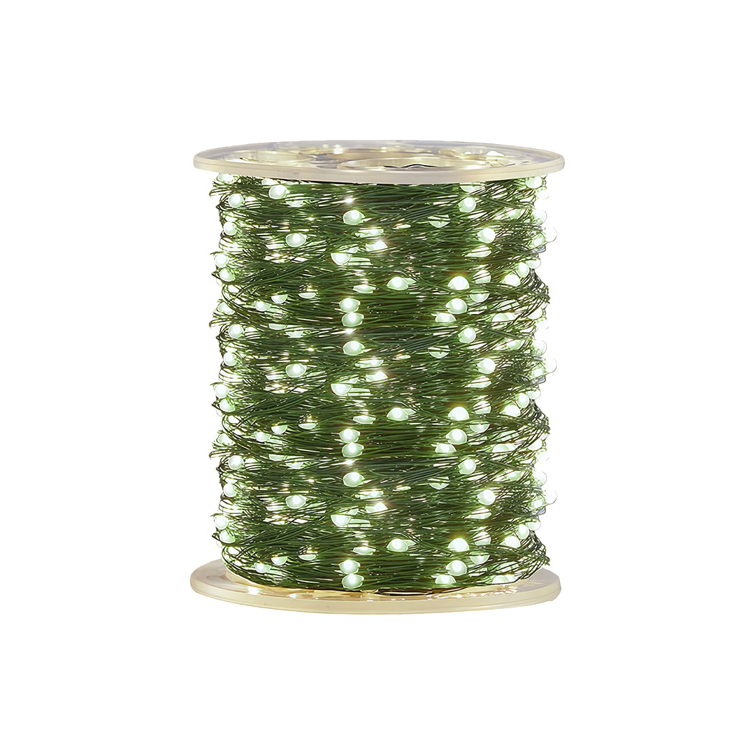 Green string Christmas lights wrapped on a single large spool against a white background.