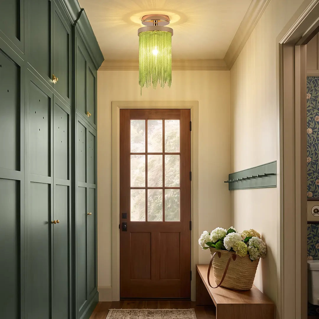 Green tassel chandelier flush mount lighting a narrow entry hallway with sage built-in cabinets and a wood front door.