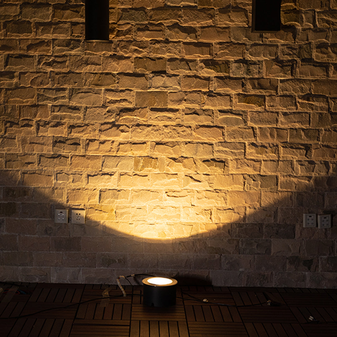 Ground-level uplighting creating stunning illumination effects on rough stone wall texture at night