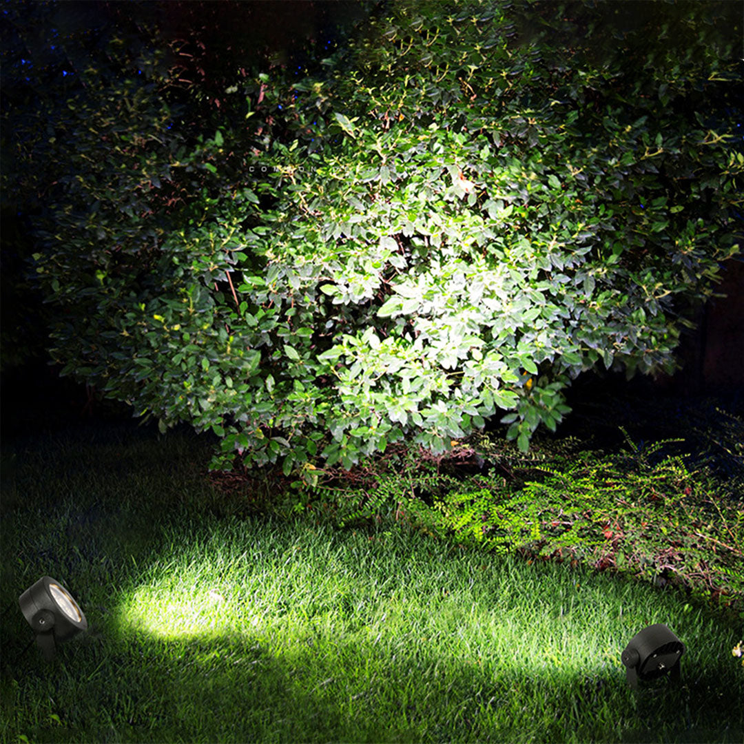 Ground-mounted waterproof LED spotlight creating dramatic uplighting effects in nighttime lawn