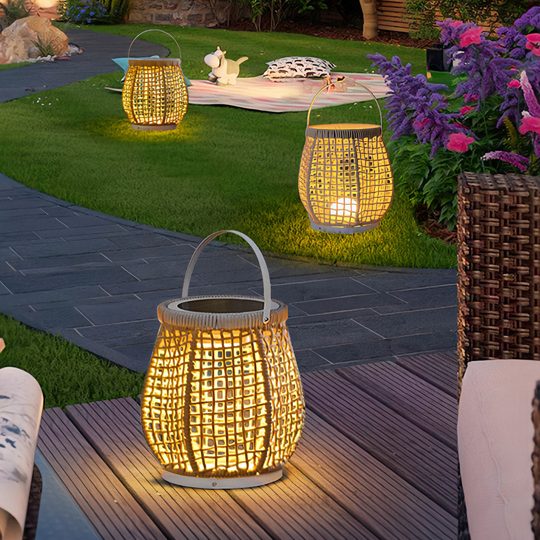 Group of woven outdoor lanterns placed on grass and decking, used as decorative solar pathway lights in a lush backyard garden setting.