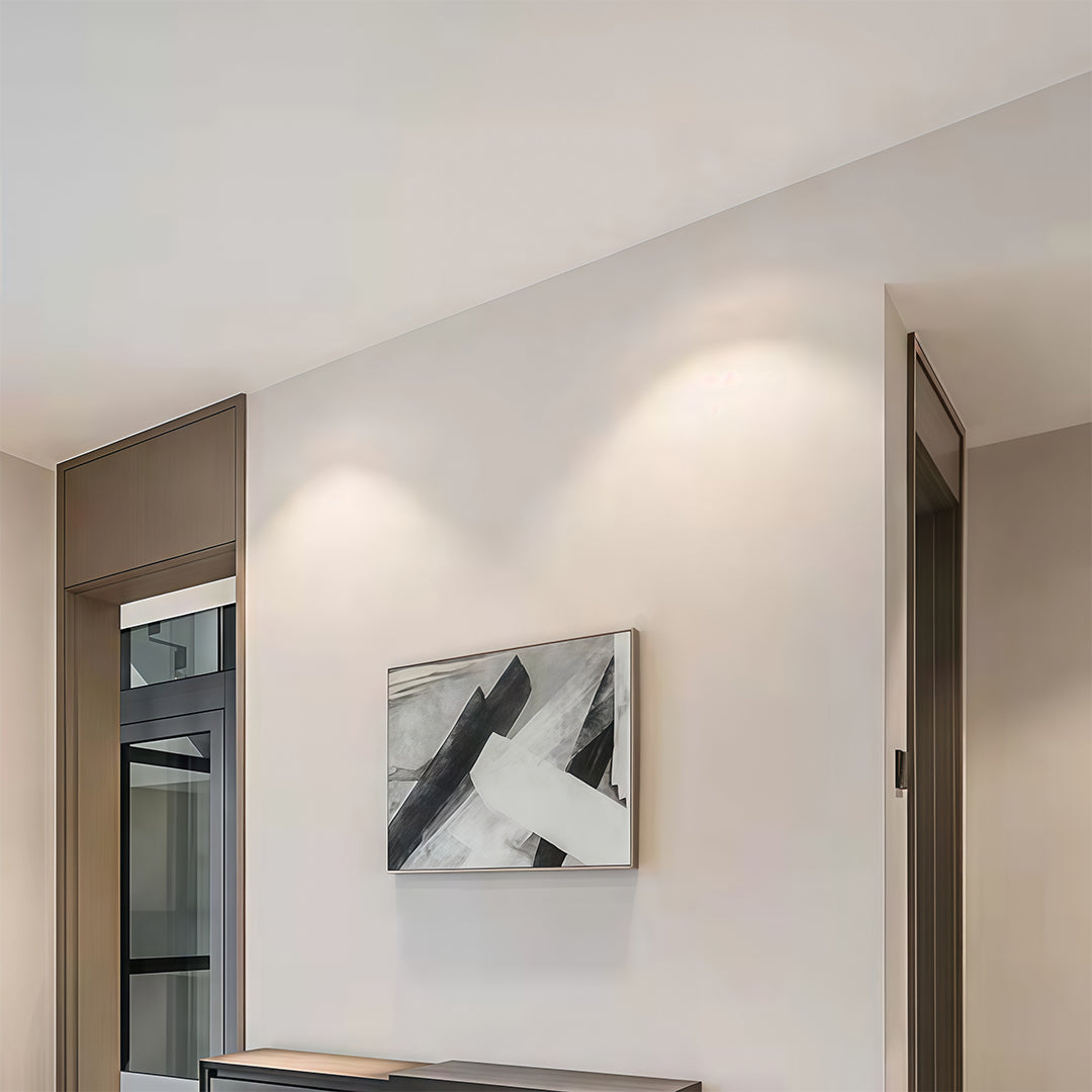 Clean hallway wall illuminated by recessed modern spotlights to highlight a piece of abstract art.