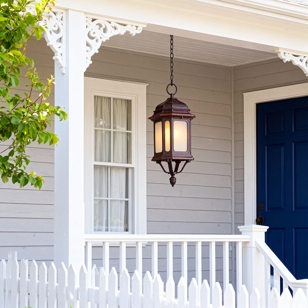 Hanging bollard LED light illuminating covered front porch entrance with white siding and navy door