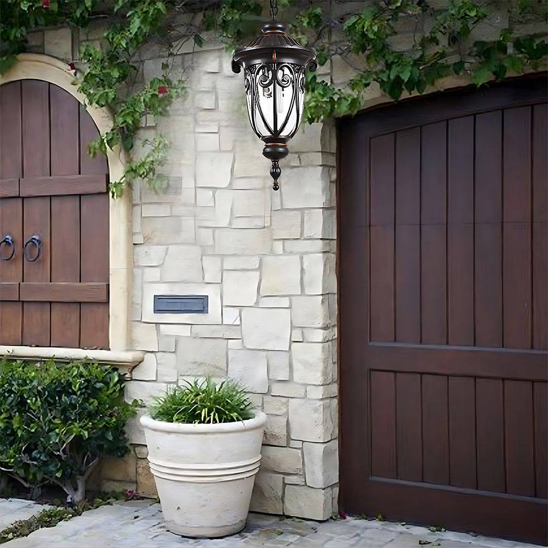 Hanging lantern mounted outside stone entrance with wooden garage doors and landscaping