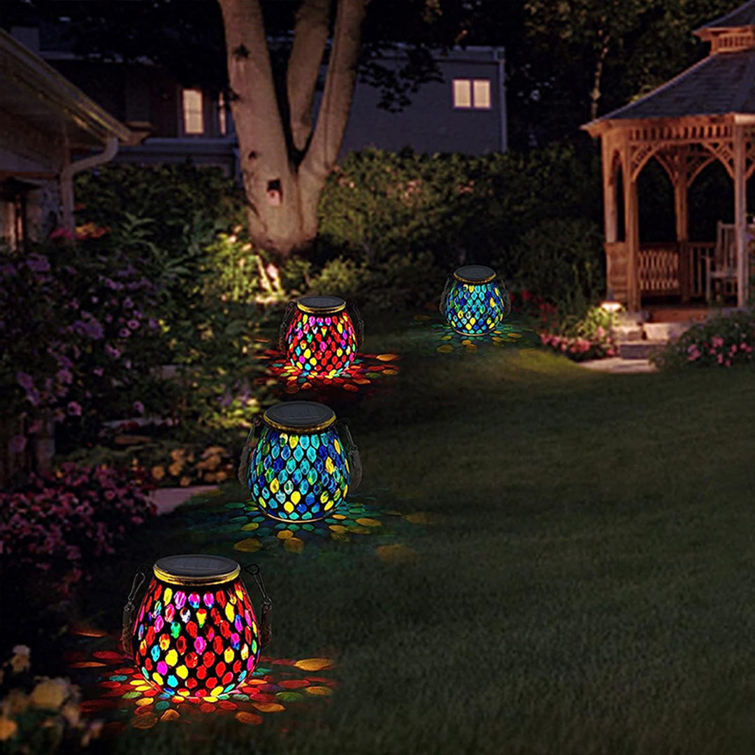 Hanging mosaic solar lanterns on tree branch providing outdoor garden illumination