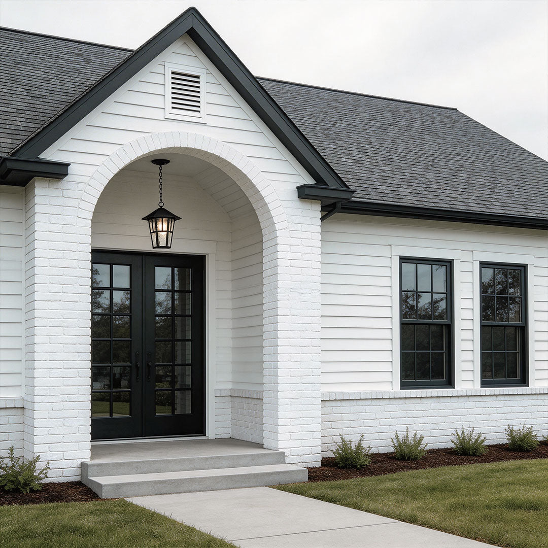Hanging outdoor light with a vintage design, mounted on a white brick house.