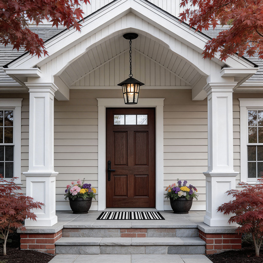 Hanging outdoor light with a vintage design, illuminating a white porch entrance.
