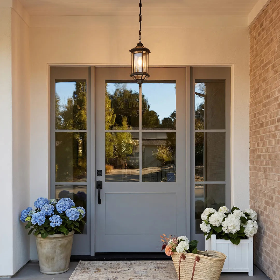 Hanging outdoor pendant lights above a front entry door with brick walls and potted hydrangeas.