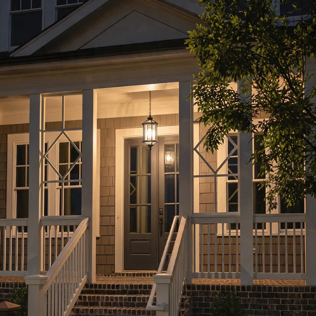 Hanging outdoor pendant lights illuminating a covered porch entry with railings and evening ambiance.