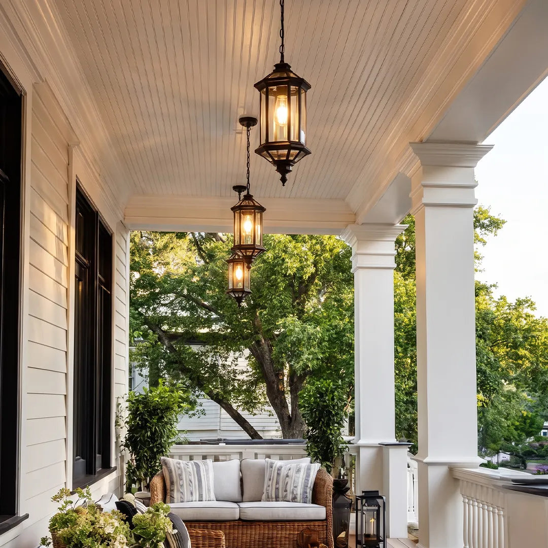 Hanging outdoor pendant lights suspended along a bright white porch with columns and cozy seating.