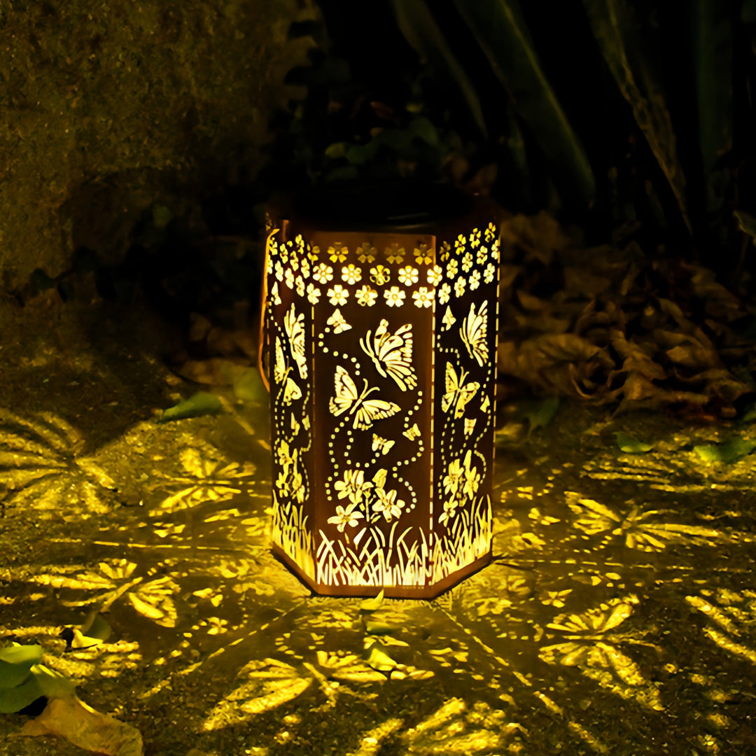 Hanging solar red outdoor lantern emphasizing the wide-spread butterfly shadow effect on pavement.