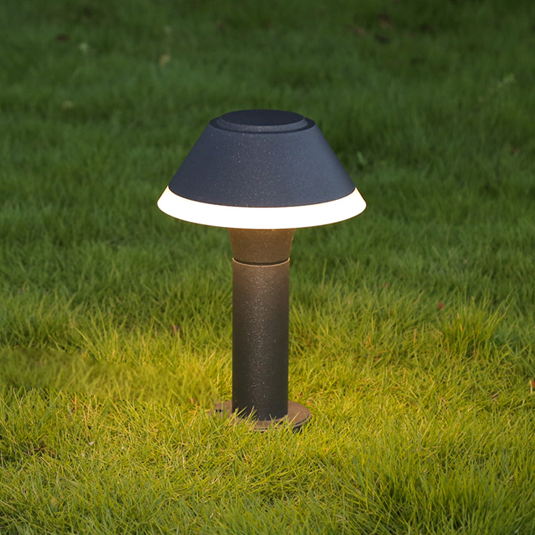 Contemporary hat-style bollard creating warm ground illumination on lawn area