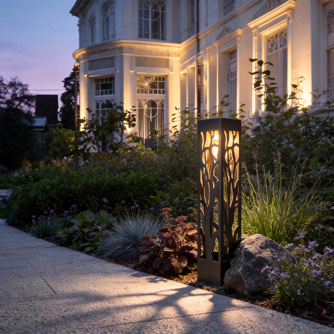 Hollow outdoor landscape lighting installed beside garden pathway creating decorative light patterns at night.