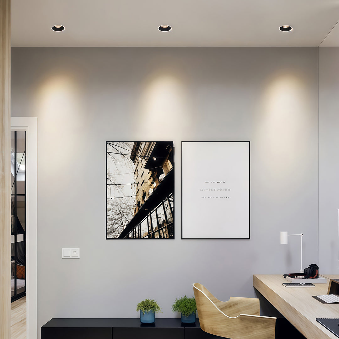 Modern home office wall illuminated by three led downlight recessed fixtures highlighting framed art.