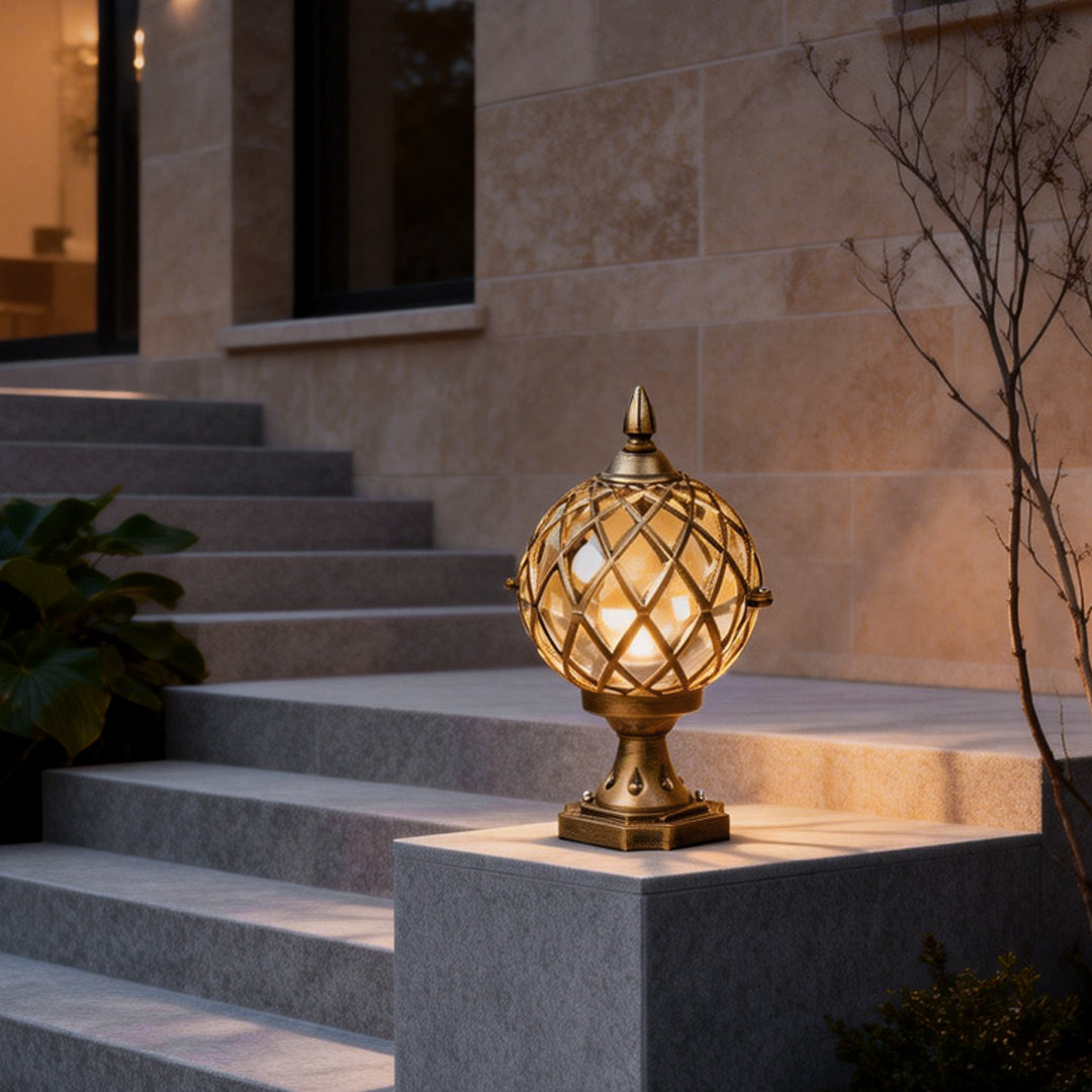 Elegant home pillar light with a gold geometric sphere design, mounted on a stone pillar at the entrance of a modern house.