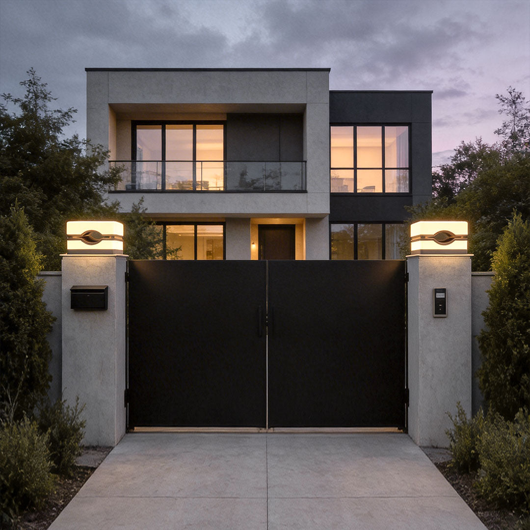 House pillar lights with a black finish installed on stone pillars near a modern fence.