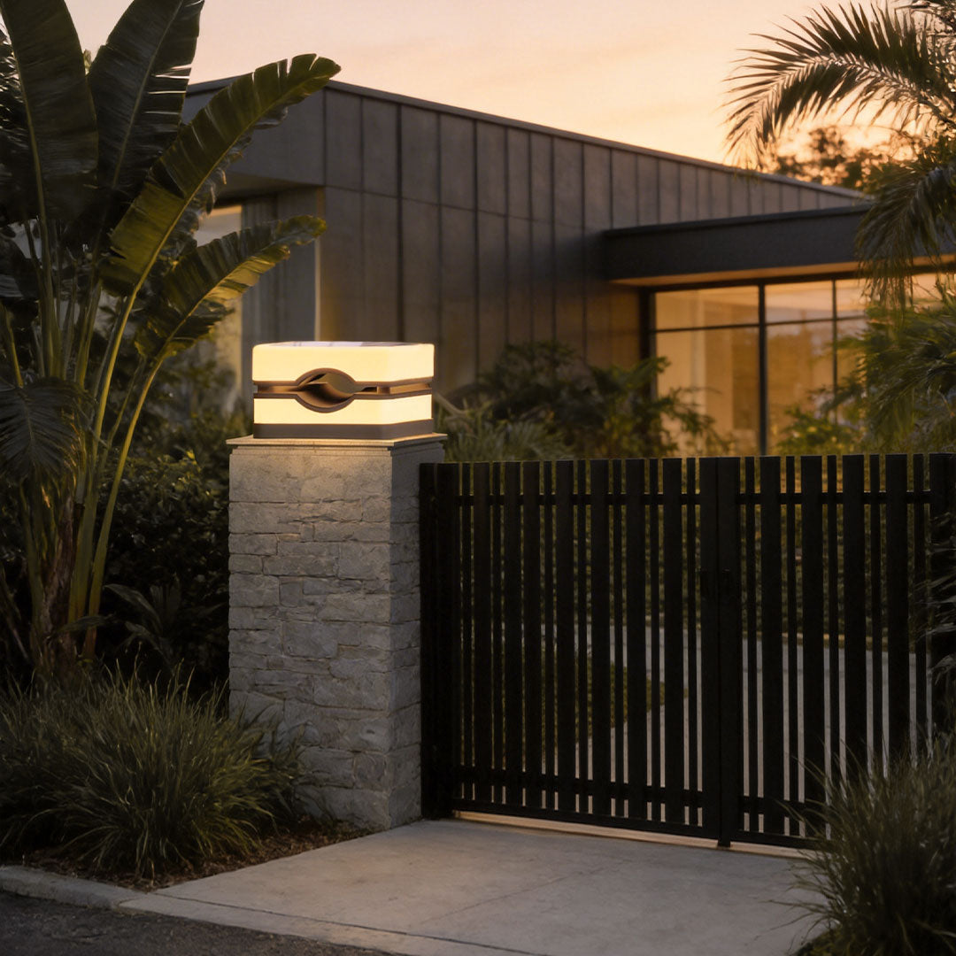 Elegant house pillar lights mounted on stone pillars beside a contemporary home with wooden accents.