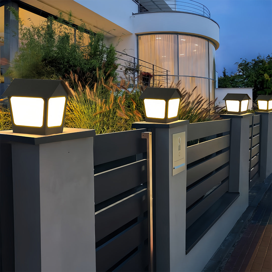House-shaped deck post cap lights mounted on a front entrance fence, enhancing security and curb appeal at night.