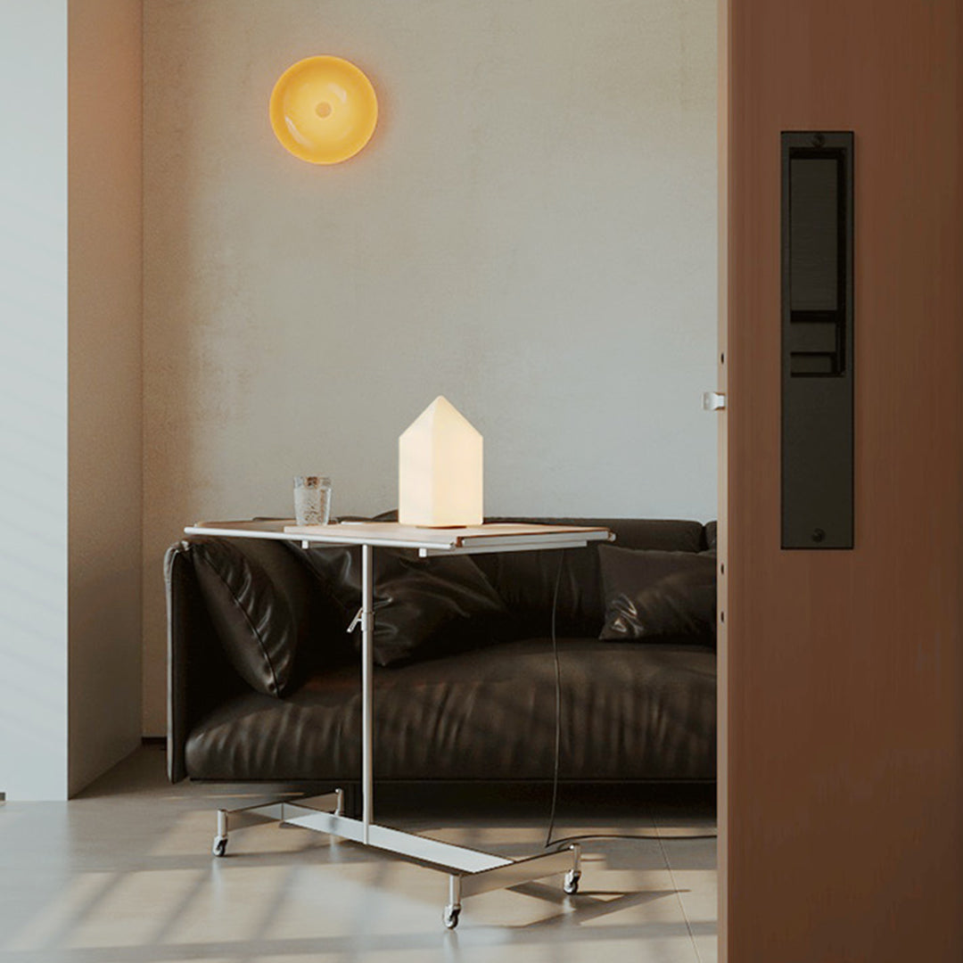 Two house-shaped table lamps on wooden boxes beside sofa.