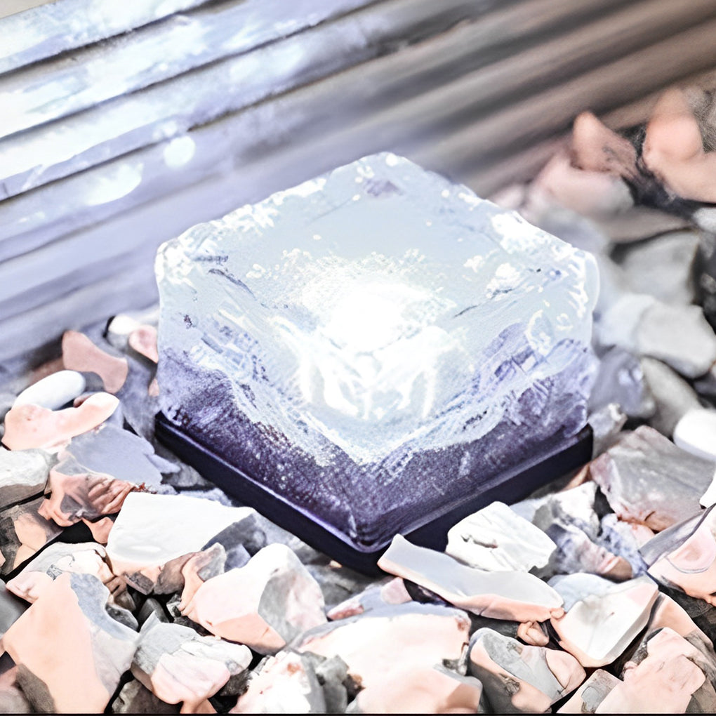 Multiple ice cube outdoor lights illuminated among dark decorative stones.