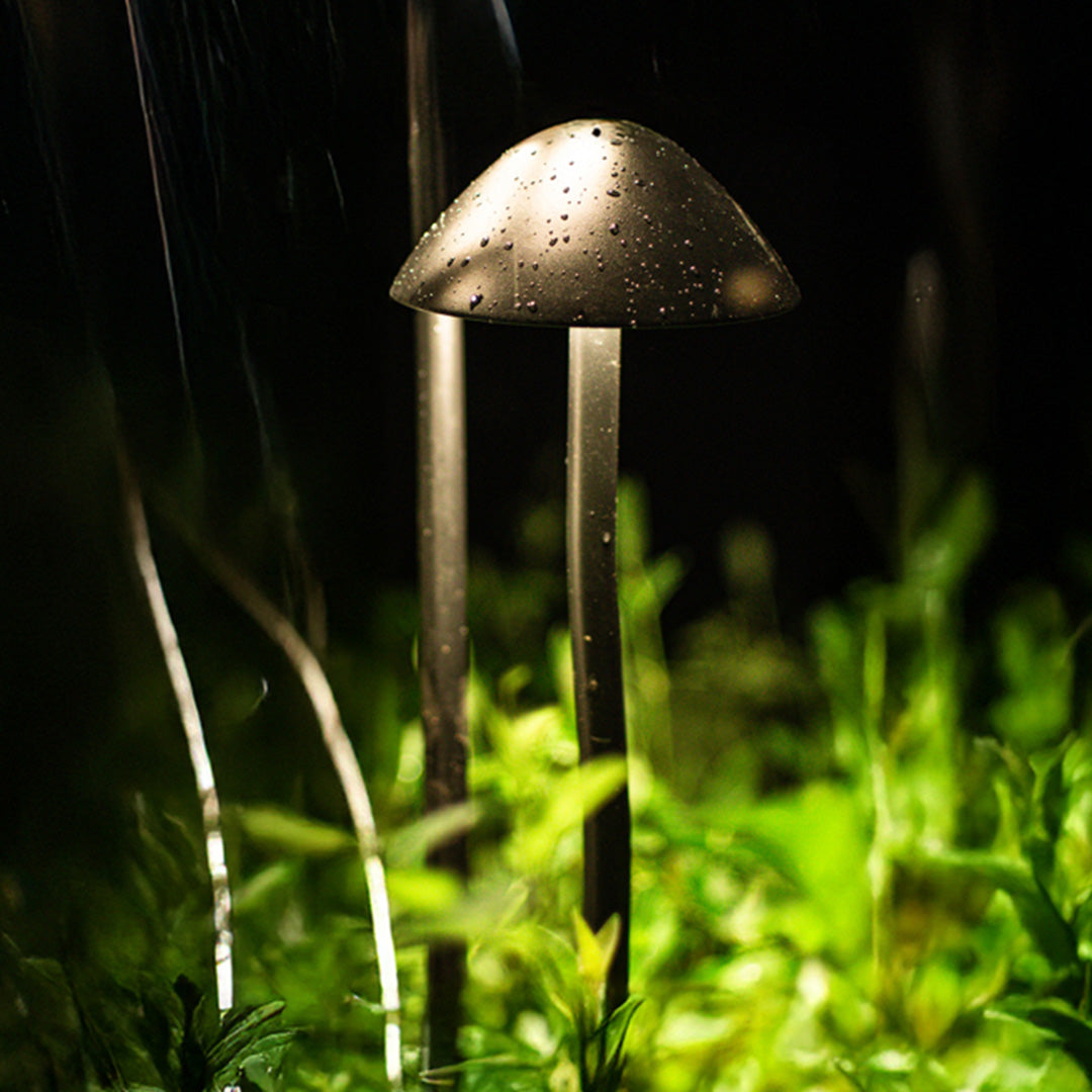 Illuminated bronze mushroom garden light creating warm atmospheric glow in natural outdoor garden setting