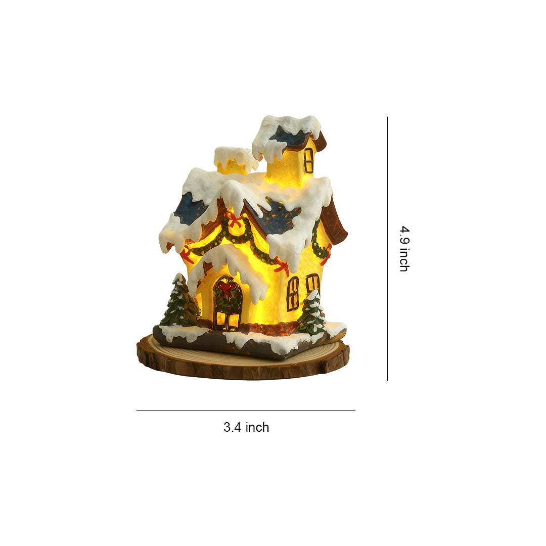 Illuminated ceramic Christmas house with snowy roof and warm yellow window lights.