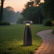 Black conical bollard light illuminating a gravel pathway in a landscaped garden.