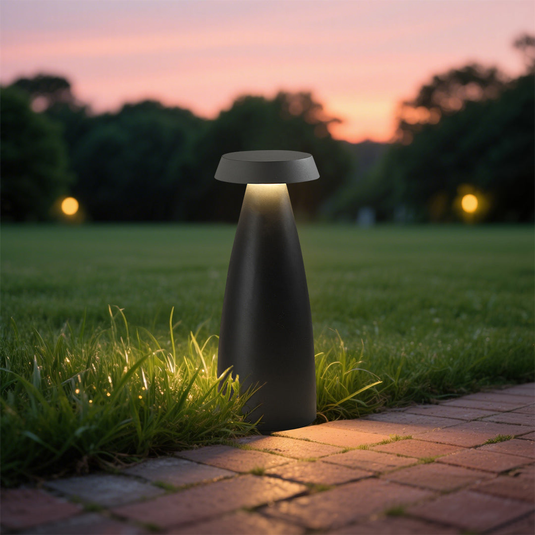 Illuminated black conical bollard light casting a warm glow in a modern outdoor setting.