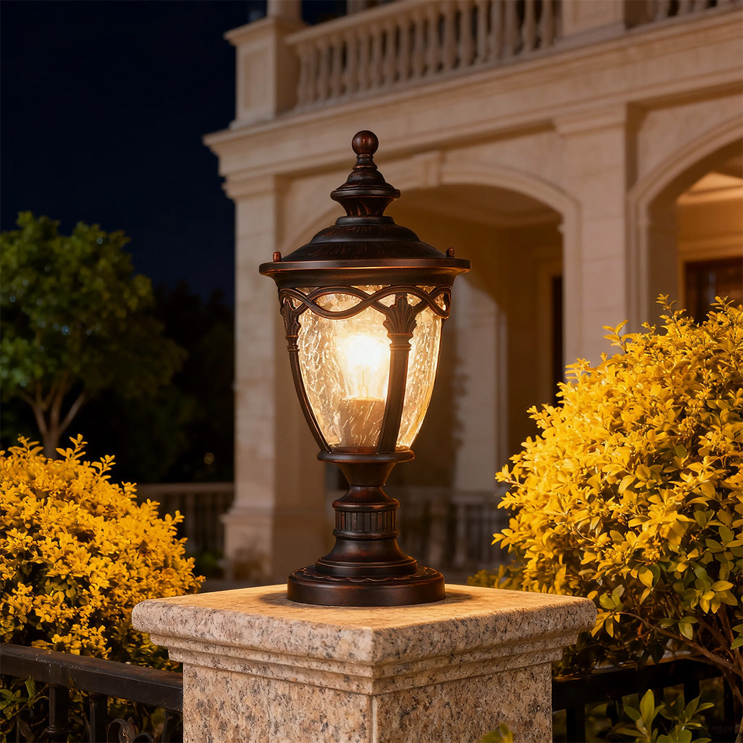 Illuminated gate pillar light casting golden glow on beige pier at dusk with yellow mums