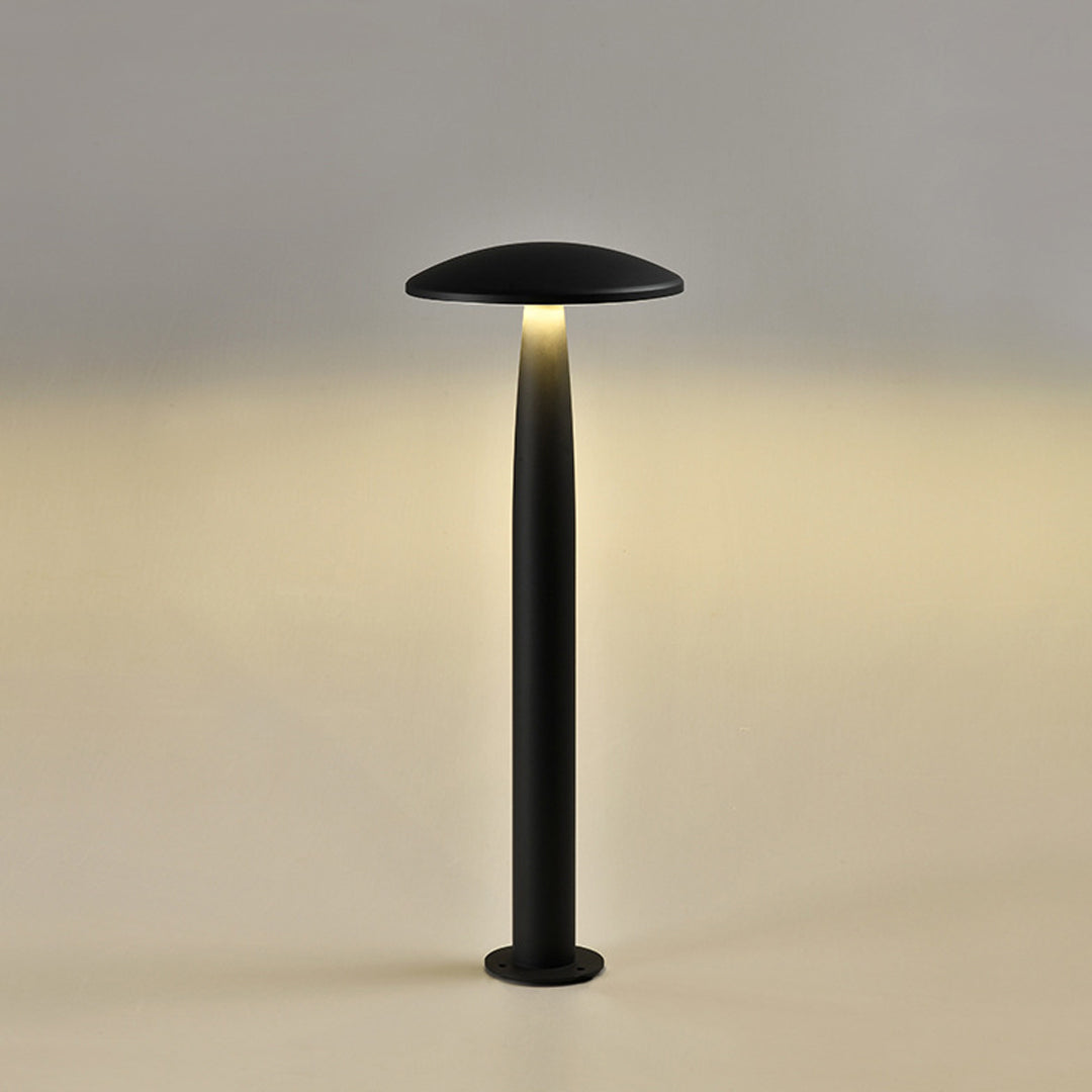Modern black mushroom bollard light illuminated at dusk, highlighting its elegant design.