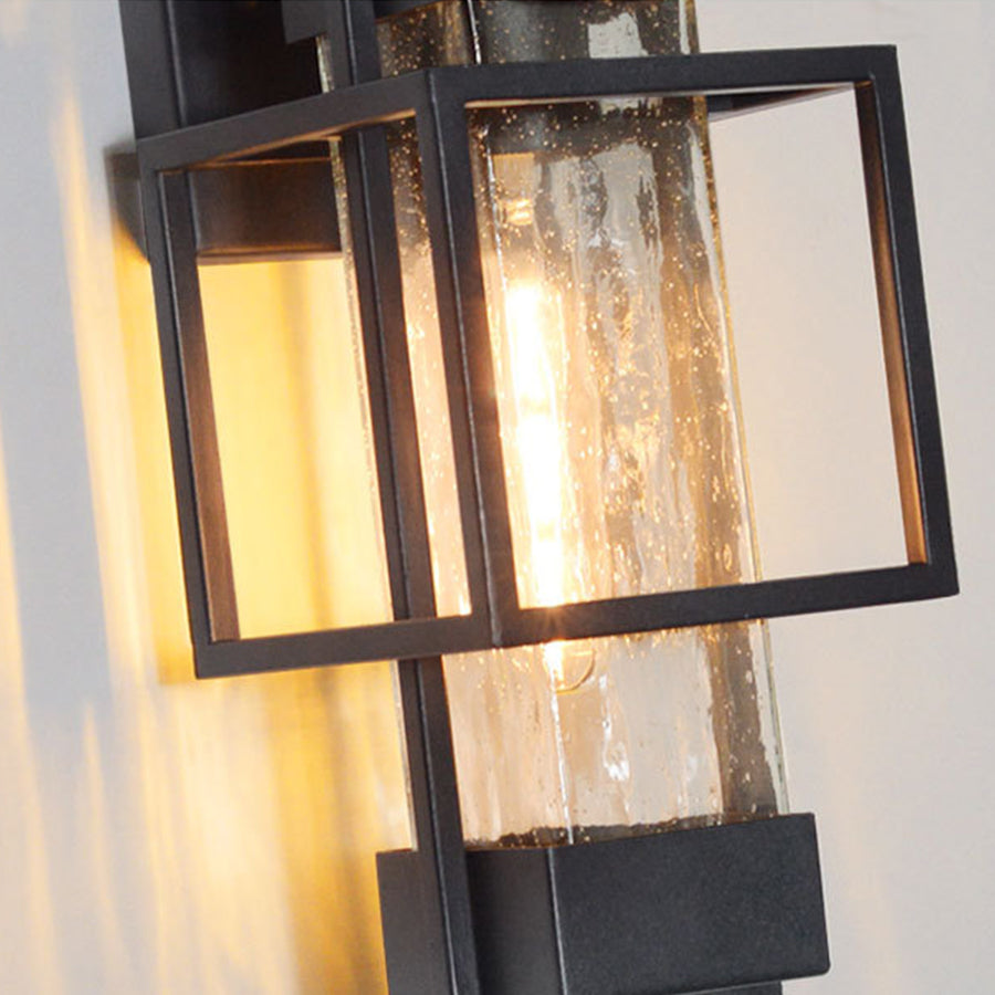 Close-up view of illuminated black outdoor lantern showing textured glass and warm light glow