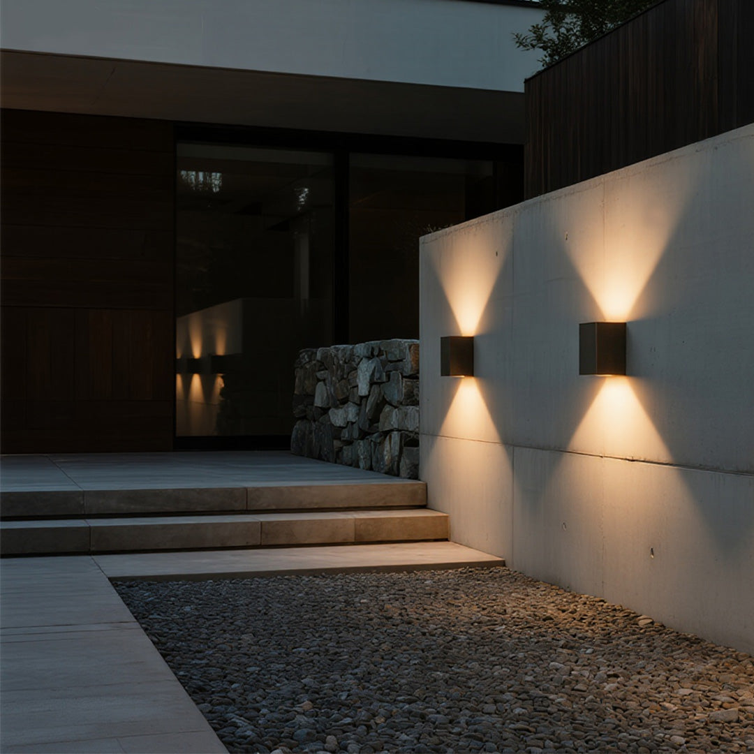 Illuminated pathway beside a stone feature wall with a pair of square Outdoor Wall Light Waterproof fixtures.