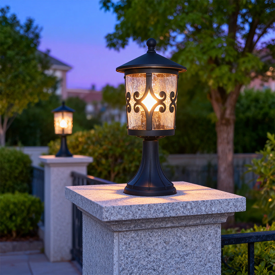 Illuminated porch pillar light mounted on grey stone pillar creating warm glow at dusk with purple sky