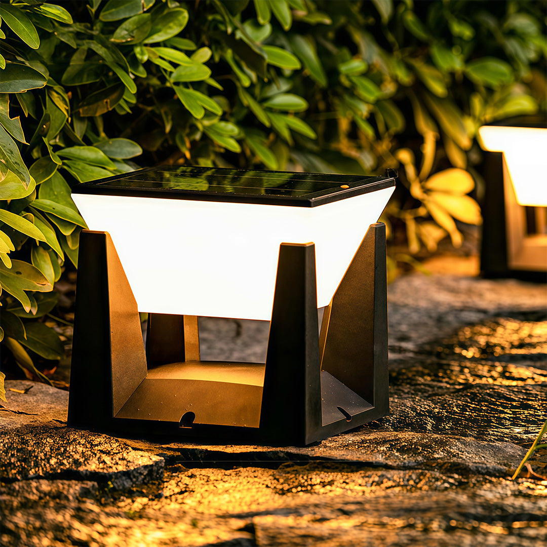 Illuminated solar bollard light fixtures lining a low stone garden wall, providing warm pathway lighting.