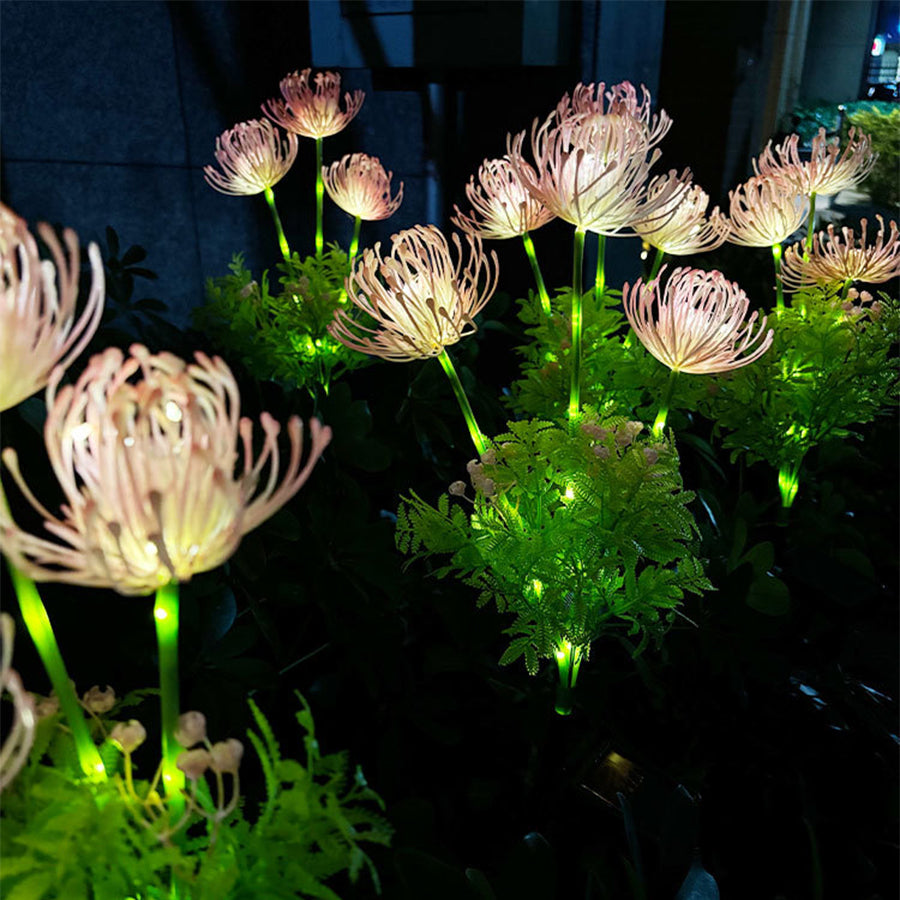 Collection of illuminated solar flower lights with warm LED glow scattered across garden landscape