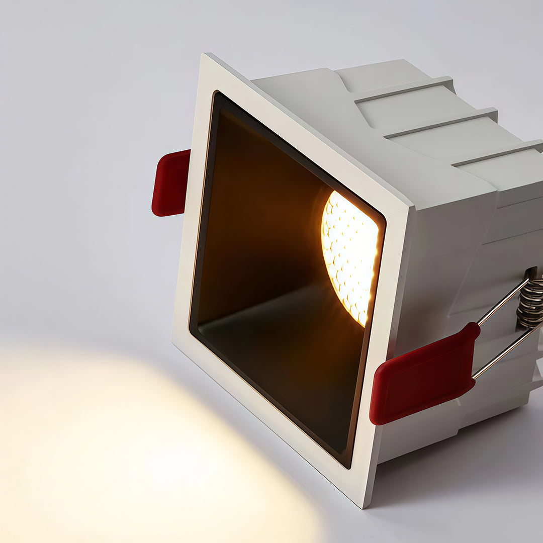 Illuminated product shot of a white recessed square led downlights fixture casting a warm glow.