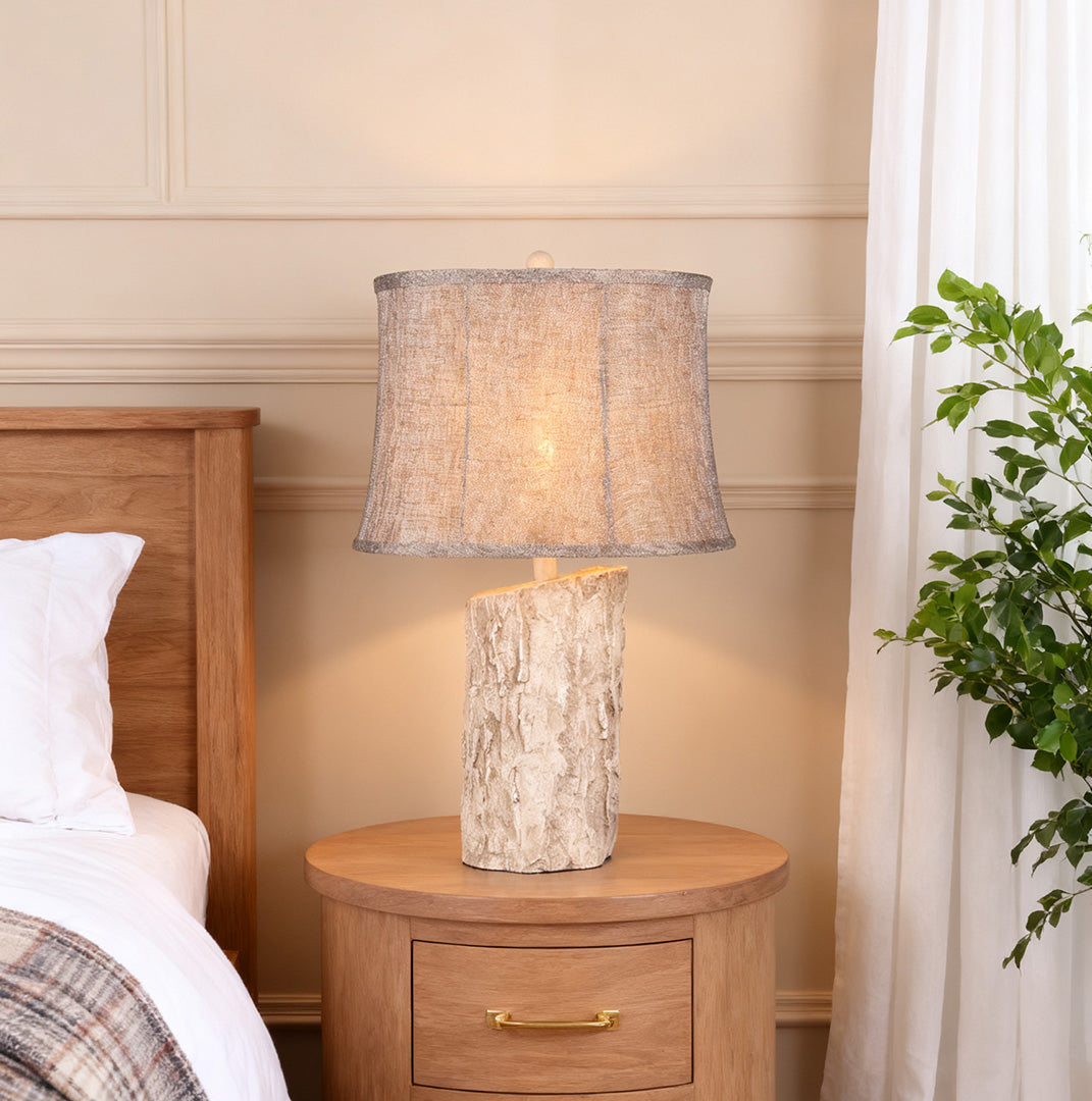 White wood table lamp illuminating a wooden nightstand, contrasting with the warm wood grain and casting a soft bedroom light.