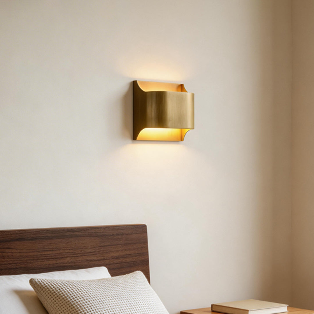 Bedroom wall decorated with brass wall light indoor spotlight lamp casting warm ambient glow on neutral wall.