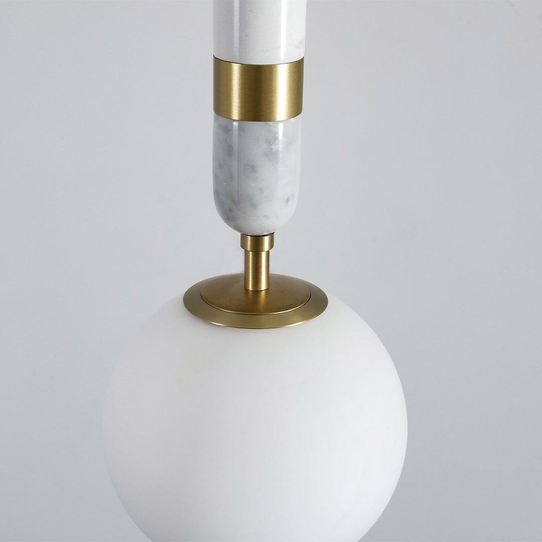 Close-up of modern globe pendant light indoor spotlight lamp showing frosted glass globe and brass accents.