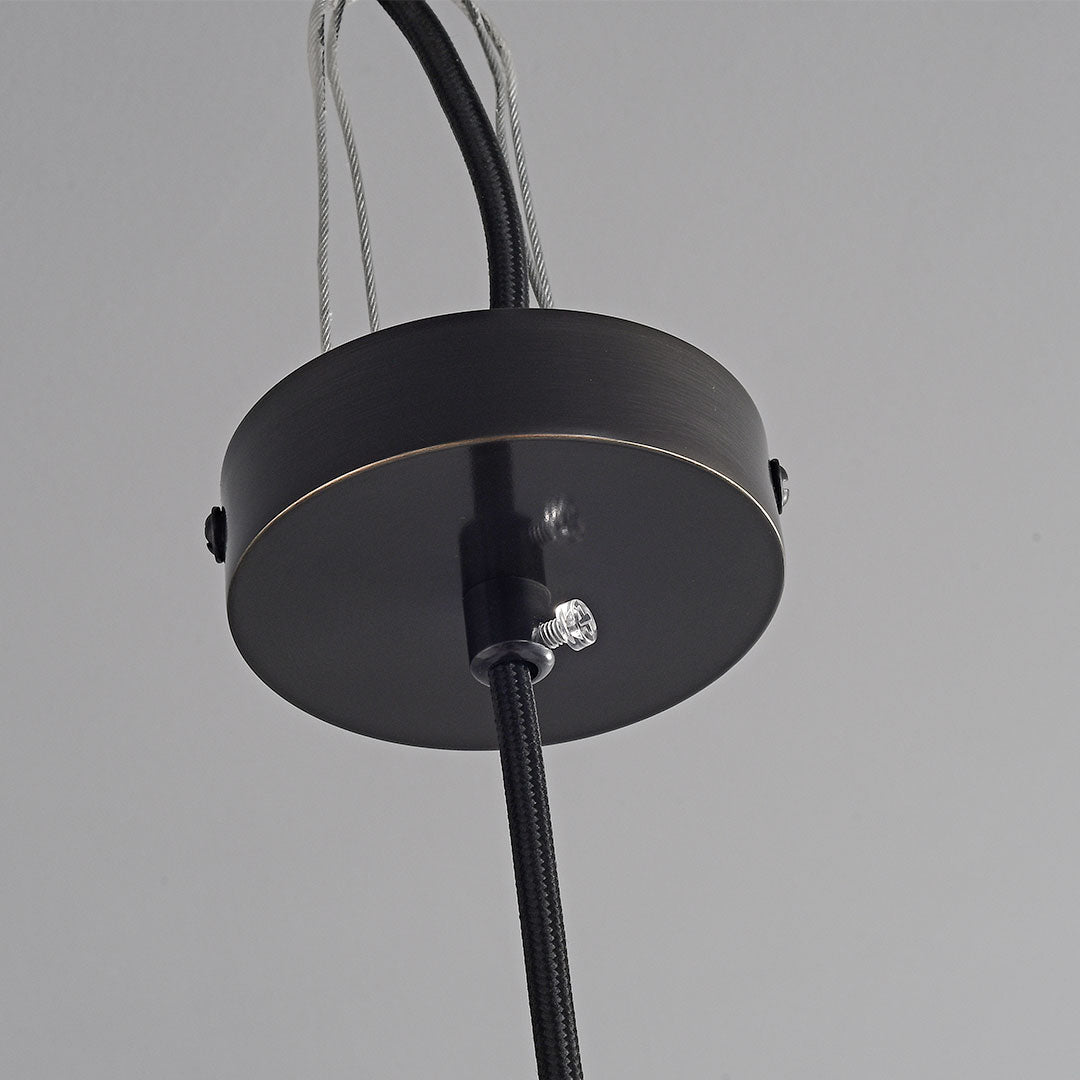 Close-up of nordic light pendant indoor spotlight lamp with brass shade and black cylindrical top design.