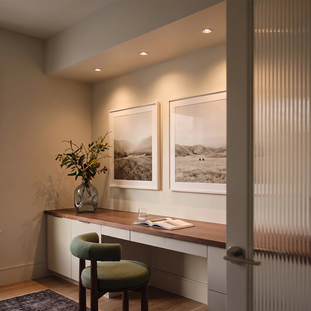 Indoor spotlights illuminating a console desk area with framed wall art and a chair.