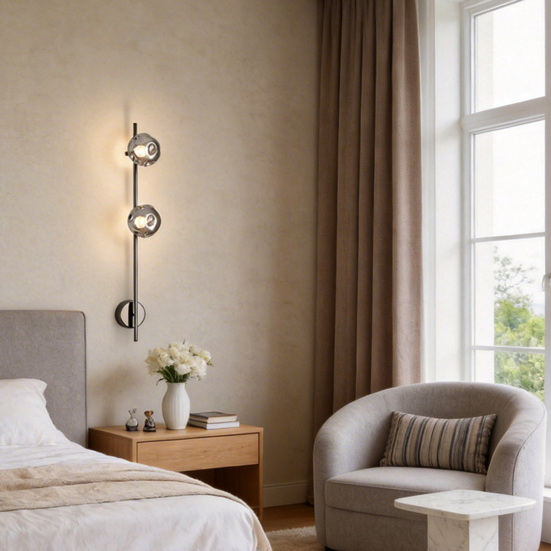 Indoor wall mounted lights with three spherical bulbs, illuminating a cozy bedroom corner.