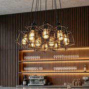 Industrial bar interior illuminated by a rectangular metal cage pendant light with exposed warm bulbs.