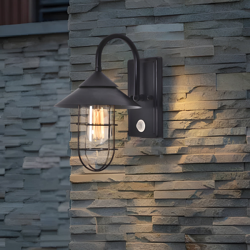Barn wall light with industrial style, fixed on a stone wall, providing warm and inviting outdoor lighting.