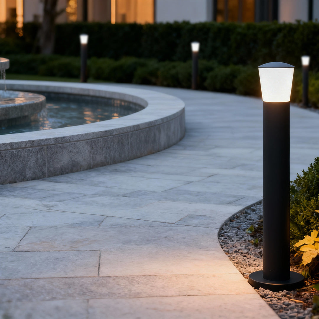 Warm industrial bollard lights illuminating a curved walkway, blending functional pathway lighting with modern style.