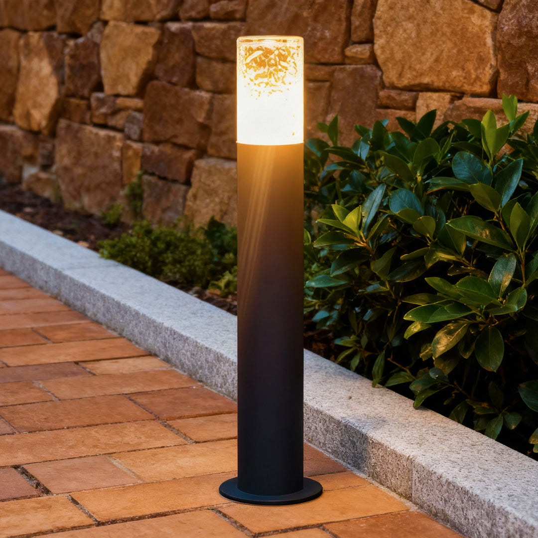 Contemporary industrial bollard lights enhancing a garden path with soft warm glow and modern cylindrical design.